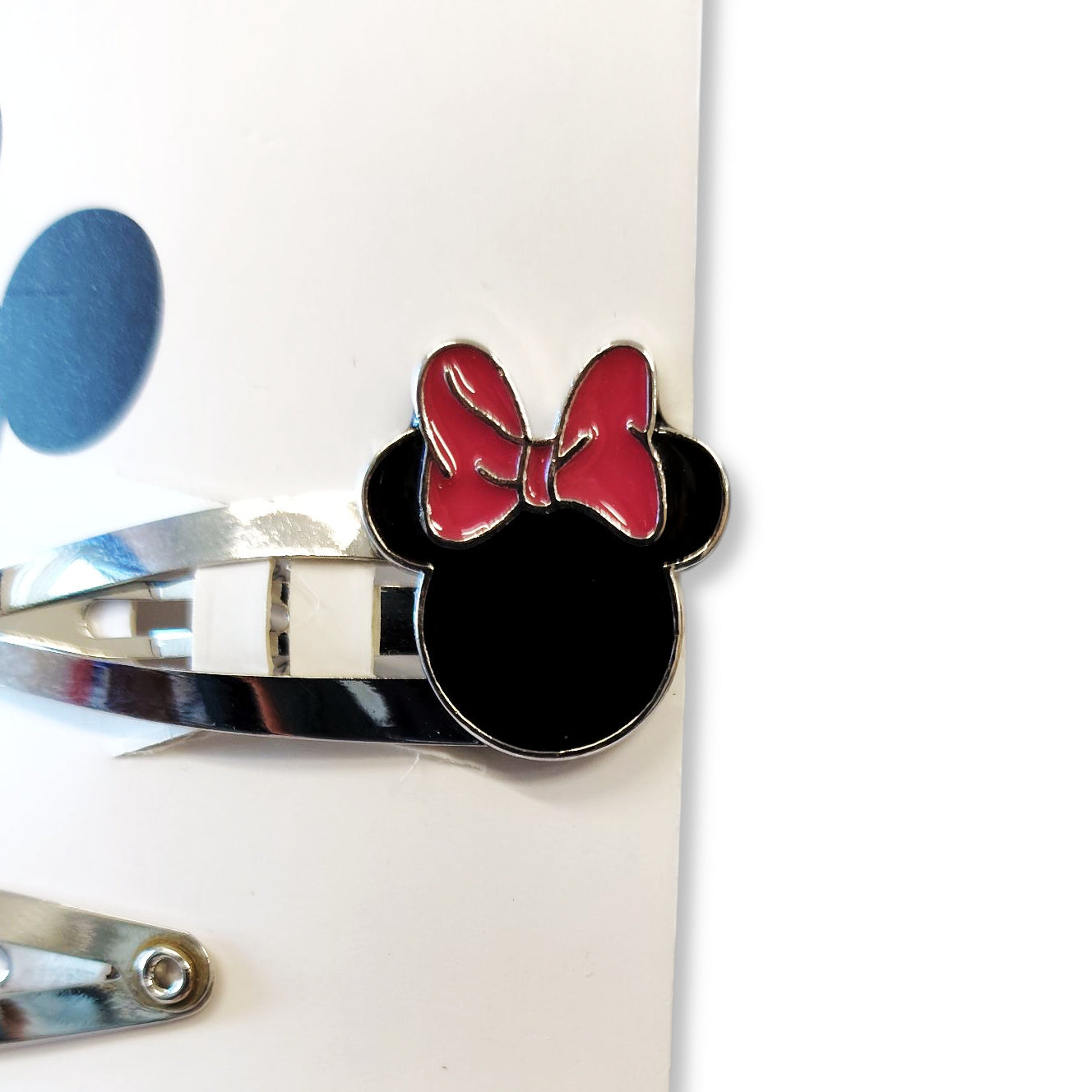Close-up detail of a pink polka-dot enamelled bow Minnie hair clip, highlighting glossy finish and snap mechanism